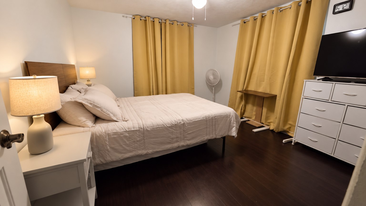 Bedroom with white bedding, bedside lamps, and mustard curtains