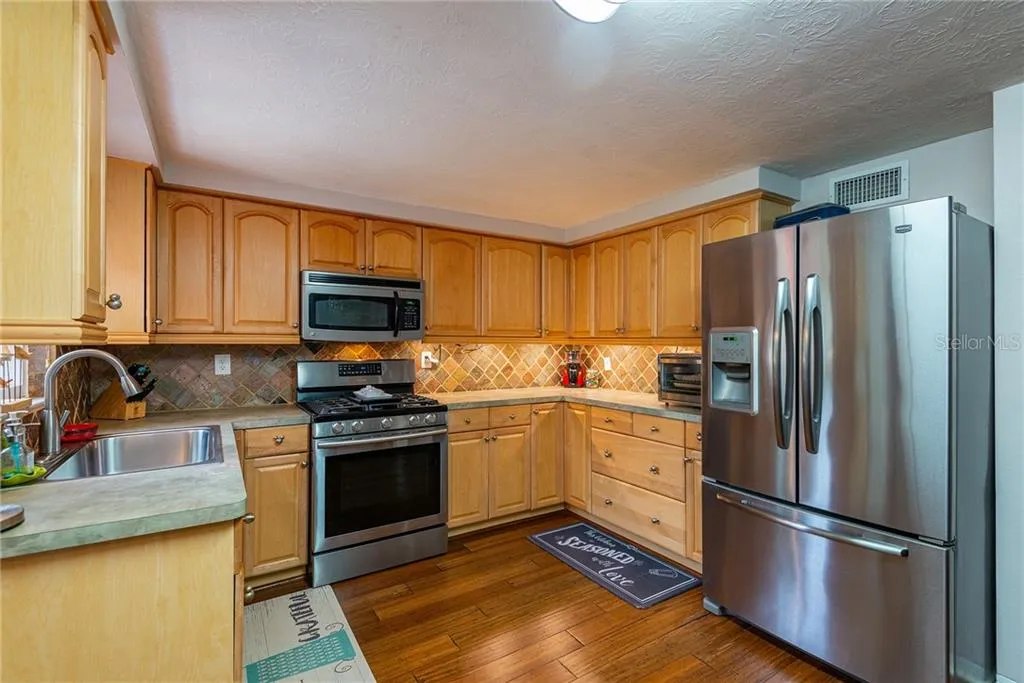 Kitchen with wood cabinetry, gas range, and stainless steel refrigerator